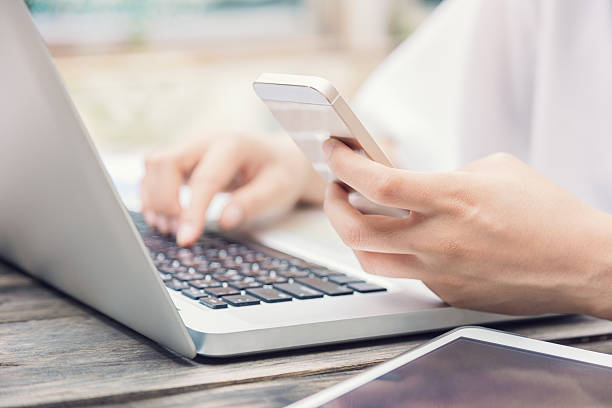 istock Female hands on laptop keyboard and smart phone 637243742