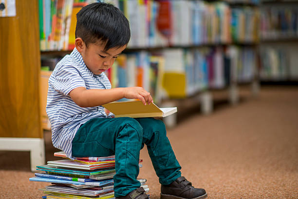 garotinho olhando para livros - people reading book library - fotografias e filmes do acervo