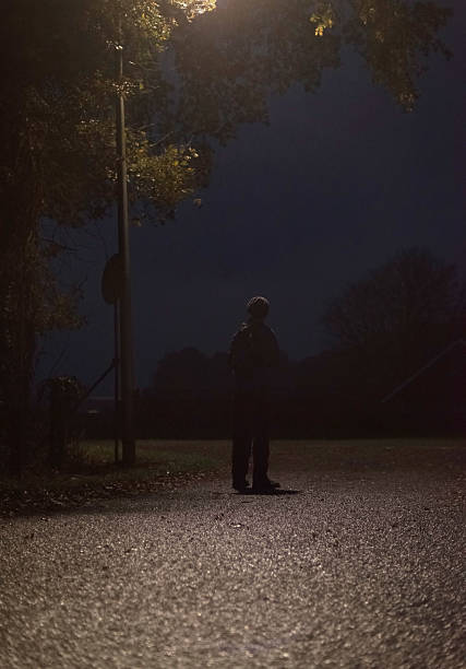 istock Lost man standing alone on rural road at night. 637253874