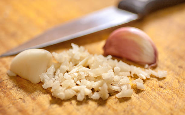 Finely cut garlic over wooden cutting board Garlic chopped over a wooden cutting board on a kitchen chop stock pictures, royalty-free photos & images