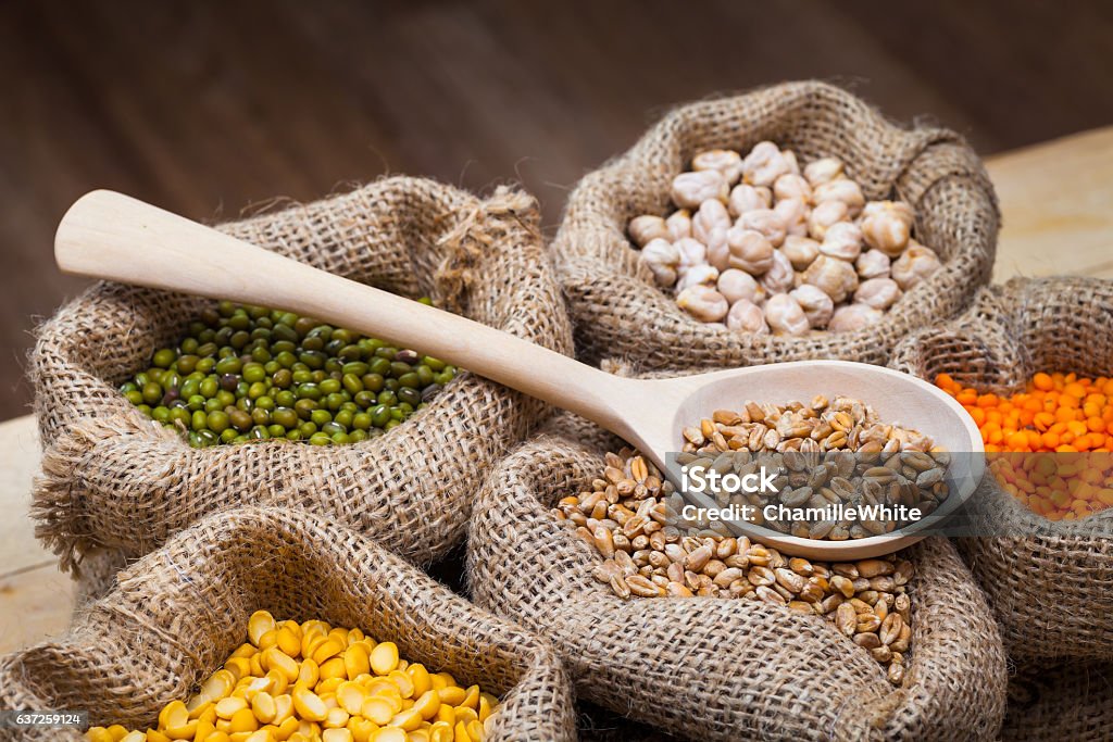 Bags of peas, chick peas, red lentils, wheat, green mung. Hessian bags with dry peas, chick peas, red lentils, wheat and green mung on kitchen table. Legume Family Stock Photo