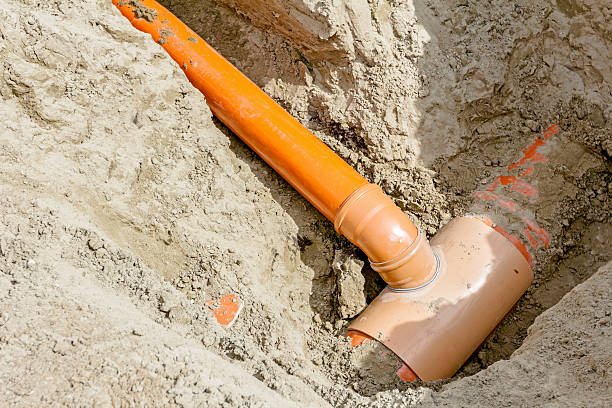 Placing set of new plastic pipes into the ground Arranged PVC of water pipes are assembled and placed in trench on building site. sewer system stock pictures, royalty-free photos & images