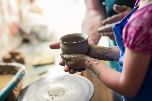 Girl holding a clay bowl made on sculpting wheel