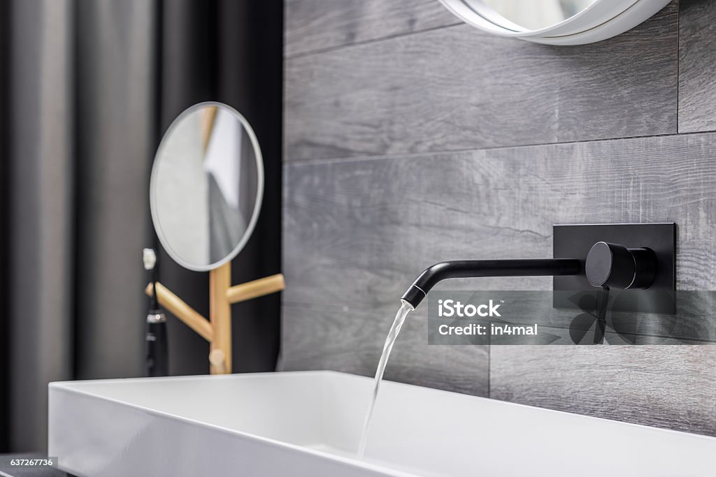 Washbasin with wall mounted tap Modern white washbasin with black tap mounted to wall Faucet Stock Photo