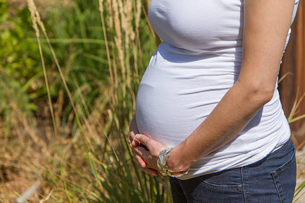 Closeup of tummy of a pregnant woman holding her belly stock photo