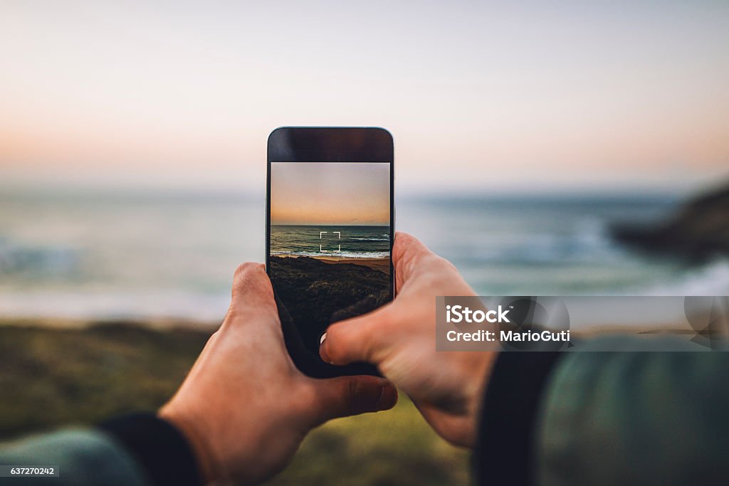 Tirando uma foto vertical ao pôr do sol - Foto de stock de Telefone royalty-free
