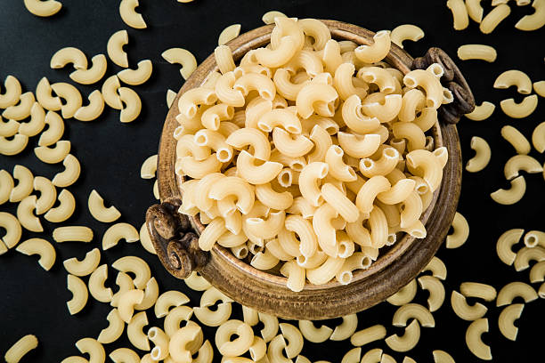 istock Macaroni pasta in the bowl on the macaroni background. 637271186