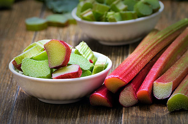 Fresh rhubarb in white bowl Fresh rhubarb in white bowl on wooden table rhubarb photos stock pictures, royalty-free photos & images