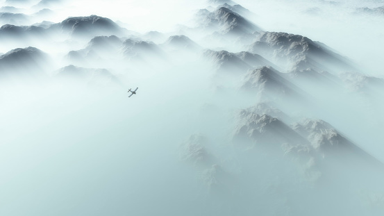 Aerial of single engine airplane over mountain range in thick layer of mist.