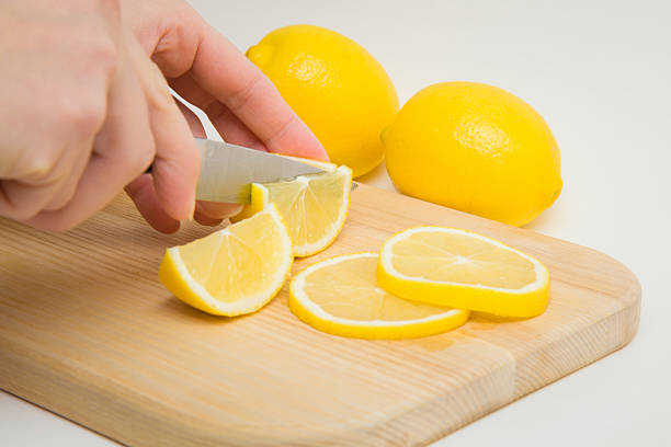 istock Hands cutting fresh, yellow lemons on the wooden board. 637274572
