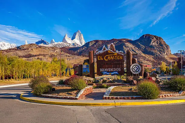 Road sign at the entrance of El Chalten village and Fitz Roy mountain on background. El Chalten located in Patagonia in Argentina.