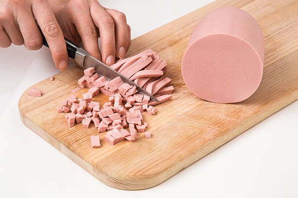 istock Woman's hand with a knife cutting a sausage for salad. 637275294