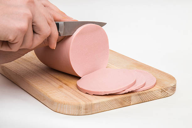istock Woman's hand with a knife cutting a sausage for sandwich. 637275322
