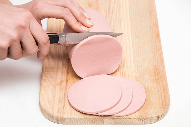 istock Woman's hand with a knife cutting a sausage for sandwich. 637275354