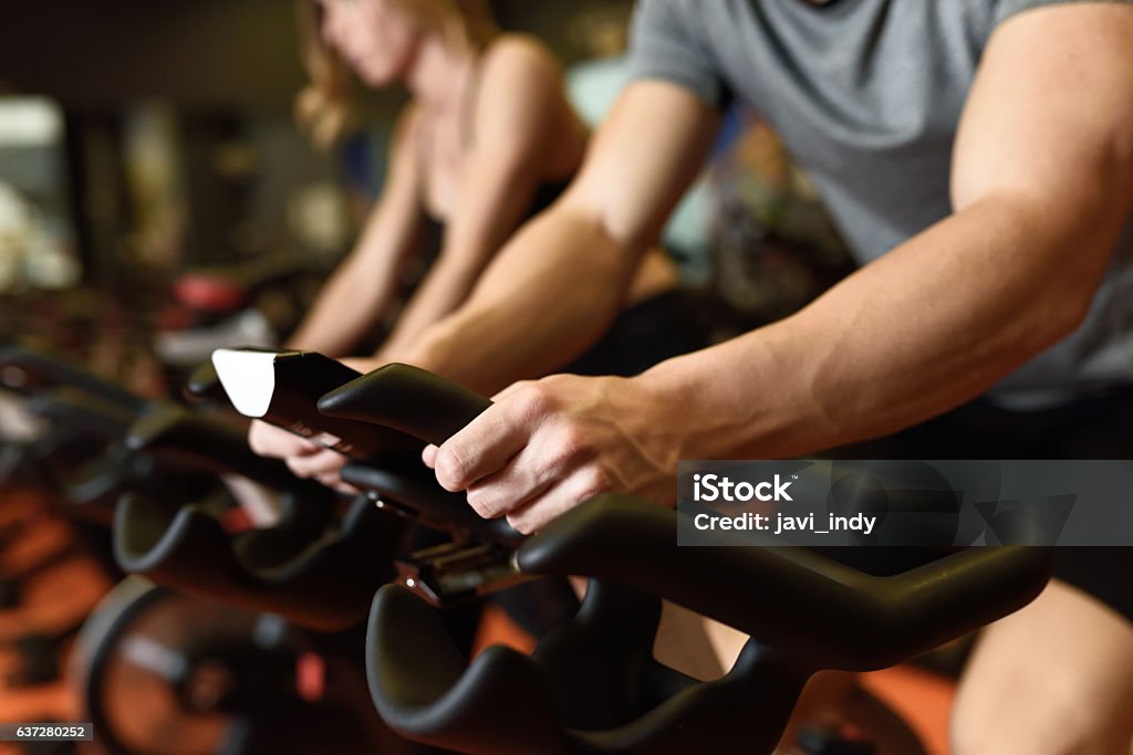 Couple in a exercising class wearing sportswear. Close-up of hands of a man biking in the gym, exercising legs doing cardio workout cycling bikes. Couple in a exercising class wearing sportswear. Spinning Stock Photo