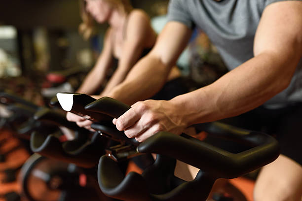 Couple in a exercising class wearing sportswear. Close-up of hands of a man biking in the gym, exercising legs doing cardio workout cycling bikes. Couple in a exercising class wearing sportswear. spin bike stock pictures, royalty-free photos & images
