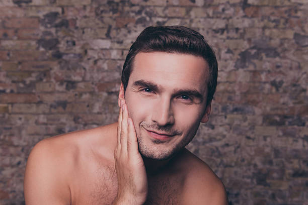 istock serious naked young man after shower touching his face 637280438