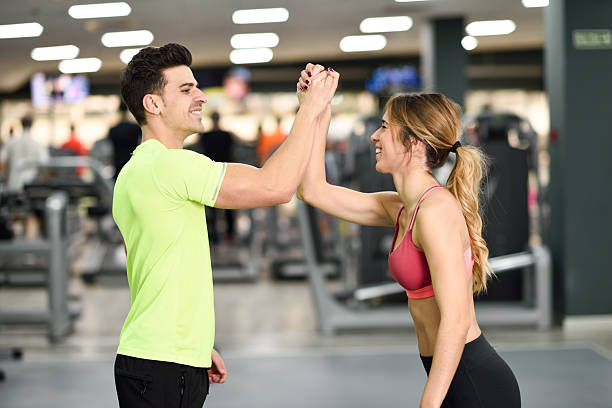istock Smiling young man and woman doing high five in gym 637280708