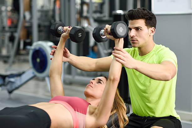 istock Personal trainer helping a young woman lift weights 637280758