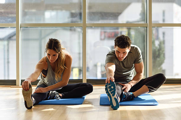 istock Two people streching their legs in gym. 637281362
