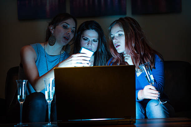 Three girlfriends, drinking champagne, watchng something interes