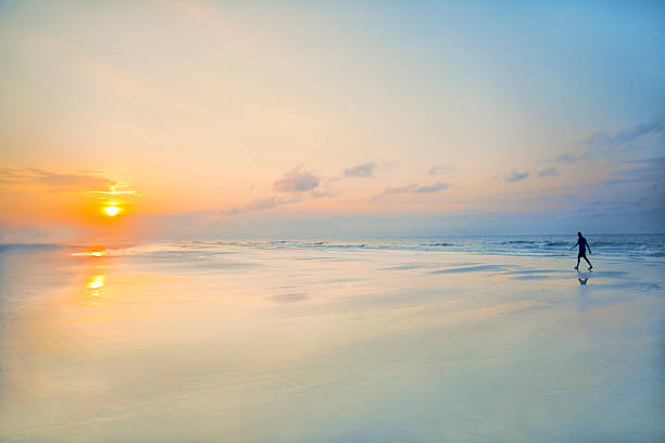 istock Man walking on beach at sunrise 637284510