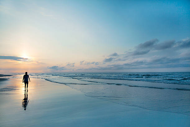 Man walking on beach at sunrise
