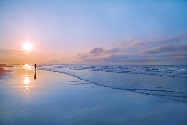 Man walking on beach at sunrise