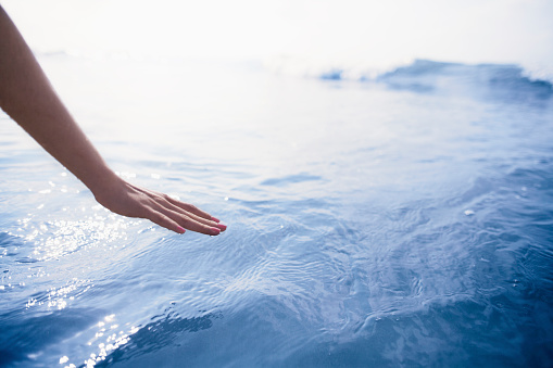 La mano de la mujer alcanzando para tocar el océano photo