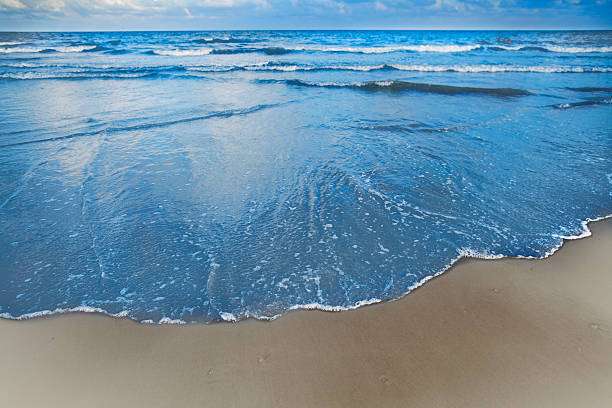 волны, поступающие на берег на пляже - high tide стоковые фото и изображения