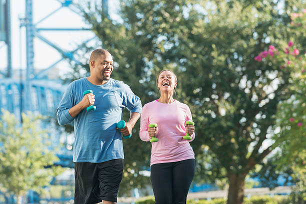 Black couple running together in park, laughing