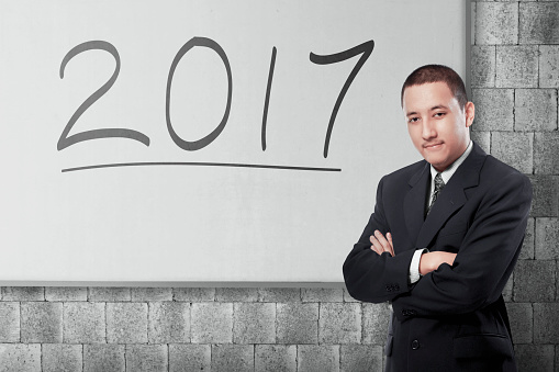 Attractive asian businessman with 2017 written on the whiteboard. New year concept.