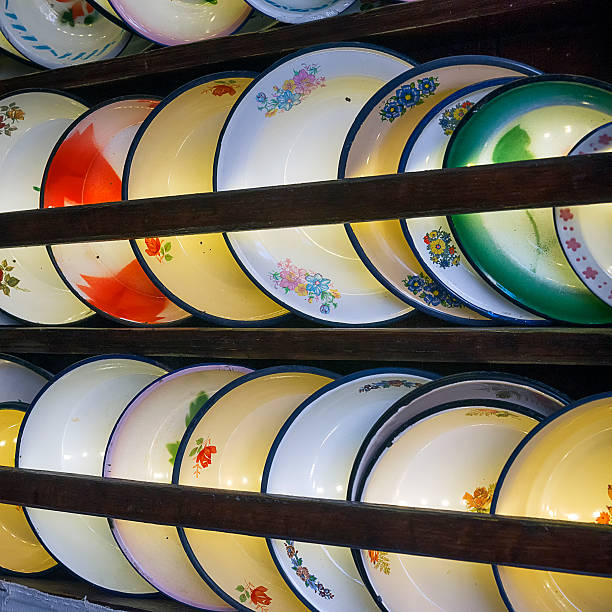 stack of vintage salad bowls on a shelf in a wooden cupboard with a soft warm sunlight. Aesthetic lifestyle photo