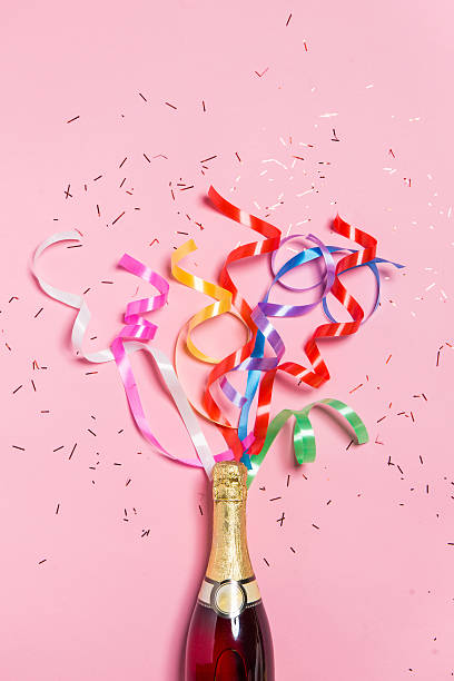 champagne bottle with colorful party streamers on pink background. - wine bottle wine residential structure alcohol imagens e fotografias de stock