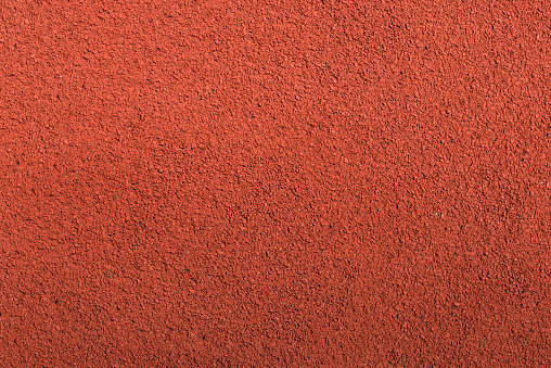 Running track rubber cover texture top view background. Closed up red crumb rubber outdoor running track surface.