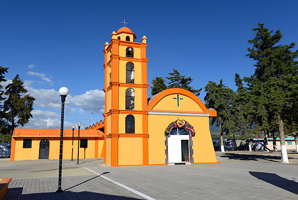 Colorful Orange Church with blue sky background, Mexico Colorful Orange Church with blue sky background located near borders of Veracruz and Puebla, close to Pico de Orizaba, Iztaccihuatland Popocatepetl volcanoes, Mexico popocatepetl volcano photos stock pictures, royalty-free photos & images