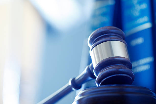 Gavel In Front Of Row Of Law Books A wooden gavel rests on its sounding block in front of a row of law books and an office interior that are out of focus in the background. Photographed using a shallow depth of field. gavel stock pictures, royalty-free photos & images