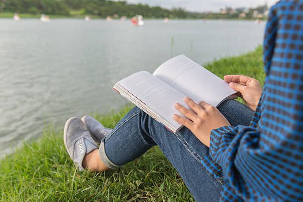istock Sitting on grass field and reading book beside lake 637294192