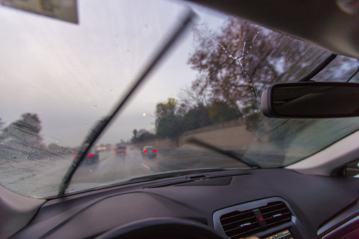 The rear view mirror of the car is covered in drops of rain.
