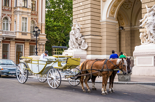 Odessa city, Ukraine June 03, 2014: Magnificent architecture and decoration of the Odessa Opera Theatre. The exterior facade of the Opera house. Art and architecture of Odessa. Vintage decorative carriage at the entrance to the Theater. Tourist attraction