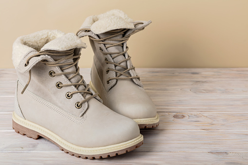 Bright leather winter boots on a light wooden background.