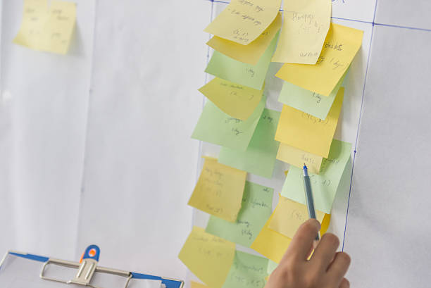 istock Close-up of human hand holding pen pointing at sticky note 637301144