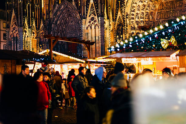 Notre-Dame cathedral with tourists and Christmas Market holidays Strasbourg, France - December 20, 2016: People walking between market stalls during Christmas Market buying food, toys, souvenirs and other traditional hand-made objects with Notre-Dame cathedral in the background notre dame de strasbourg stock pictures, royalty-free photos & images
