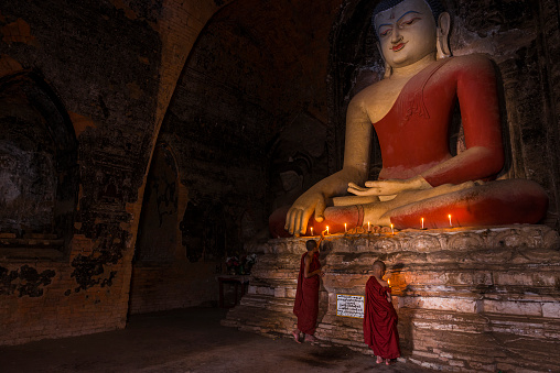 Two young buddhist monks praying inside the temple in Bagan,