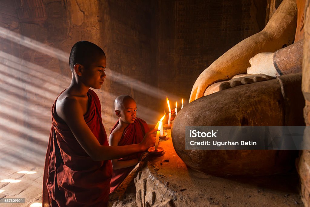Young buddhist monks in Two young buddhist monks praying inside the temple in Bagan, Monk - Religious Occupation Stock Photo