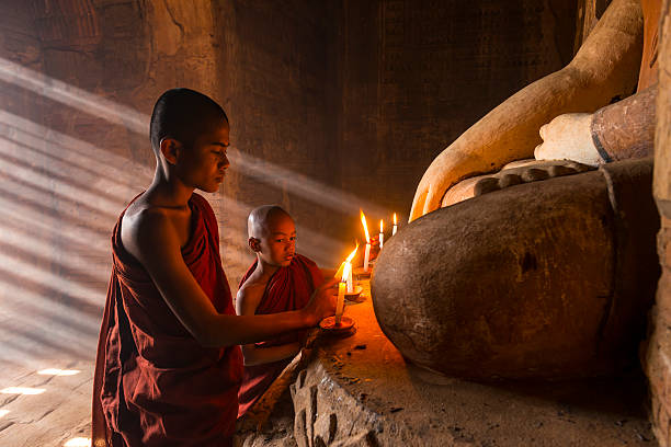 Young buddhist monks in Two young buddhist monks praying inside the temple in Bagan, bagan archaeological zone stock pictures, royalty-free photos & images