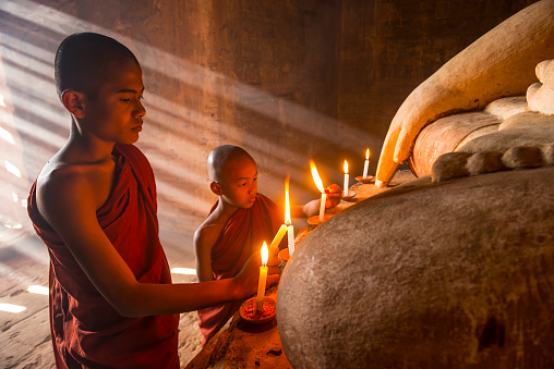 Two young buddhist monks praying inside the temple in Bagan,