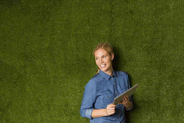 istock Young woman posing with tablet by green wall 637304200