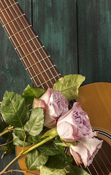 istock Guitar neck with tender pink roses on dark background 637306410