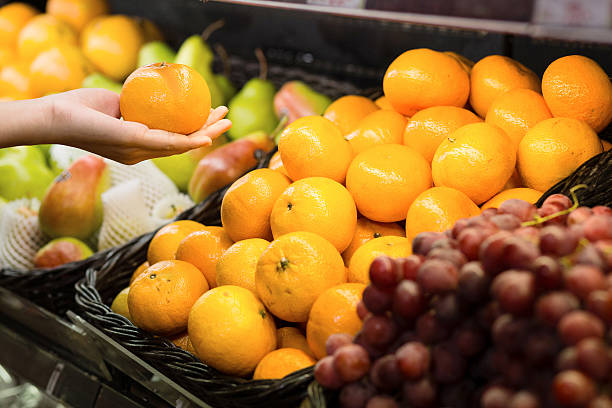 istock woman's hand choosing orange in supermarket 637311002